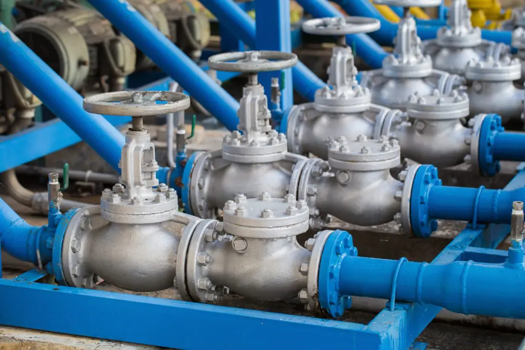 Metal valves connected to blue industrial pipes.