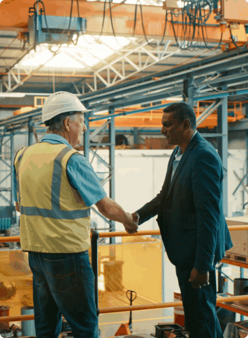 Two men shaking hands in factory.